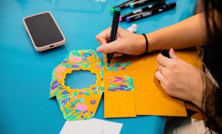 Hands decorating an unfolded box on a blue surface