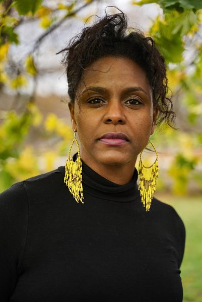 Headshot of person with medium dark skin and dangly earrings outside
