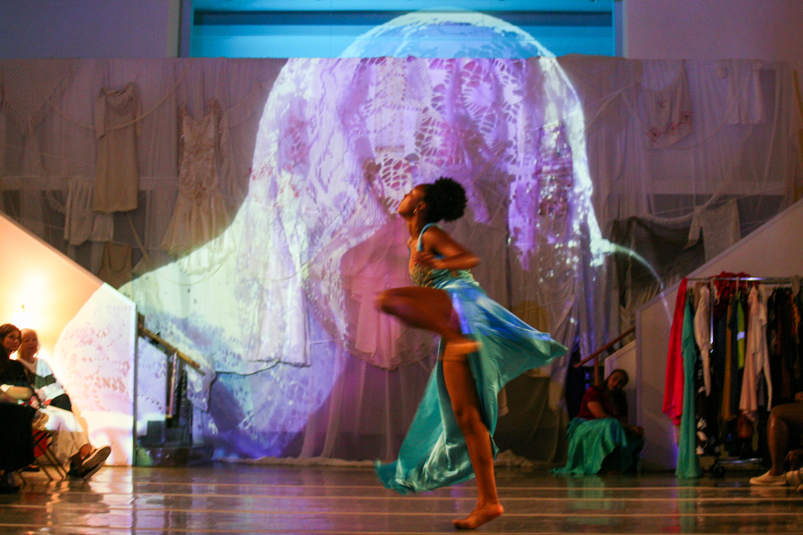 a woman in a teal dress dances on a stage