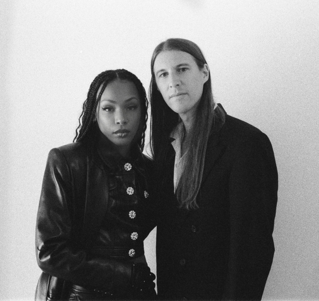 Black and white photo of two people with long hair dressed in dark clothing