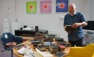 Brian Eno looking at book surrounded by studio space