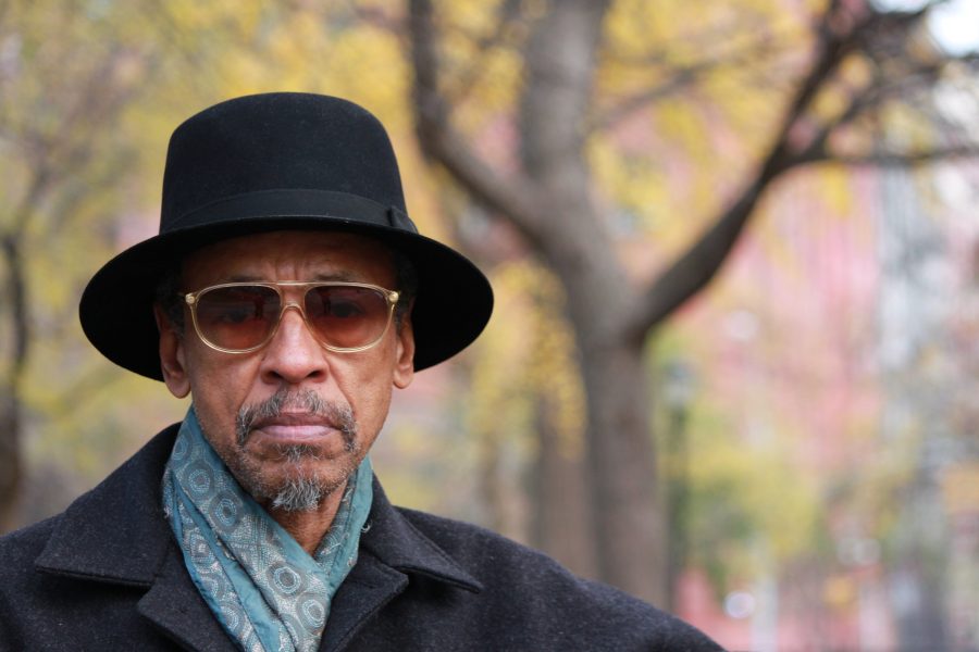 Person with medium colored skin wearing sun glasses and black brimmed hat outside