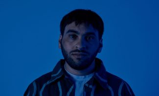 Photo of person with short hair and a beard in dark blue lighting