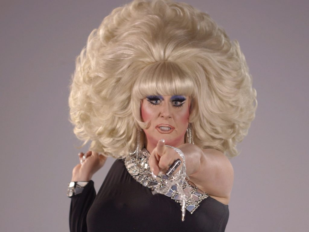 Drag queen Lady Bunny with big blonde wig pointing at viewer