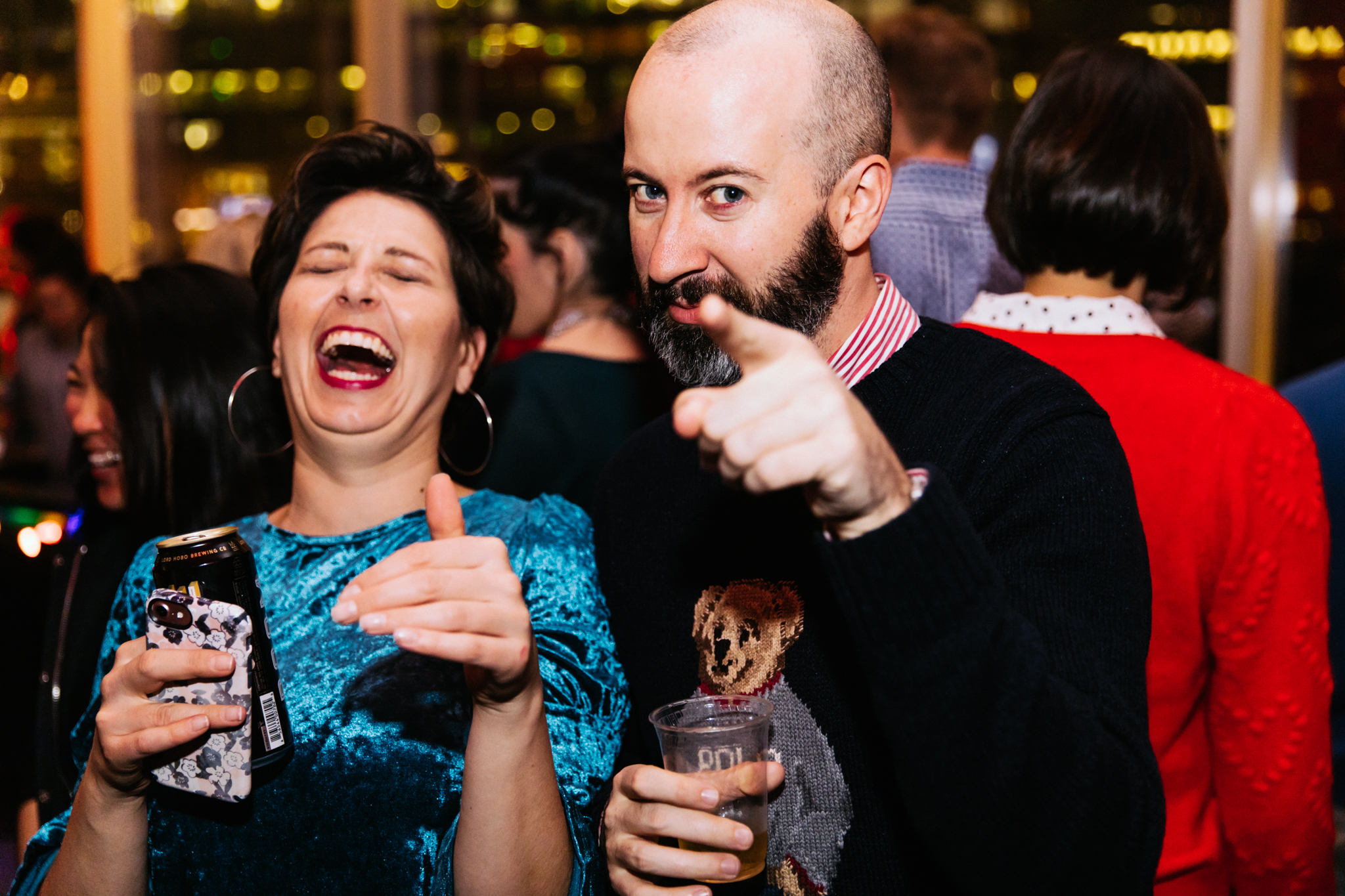 Two people wearing sweaters and holding drinks