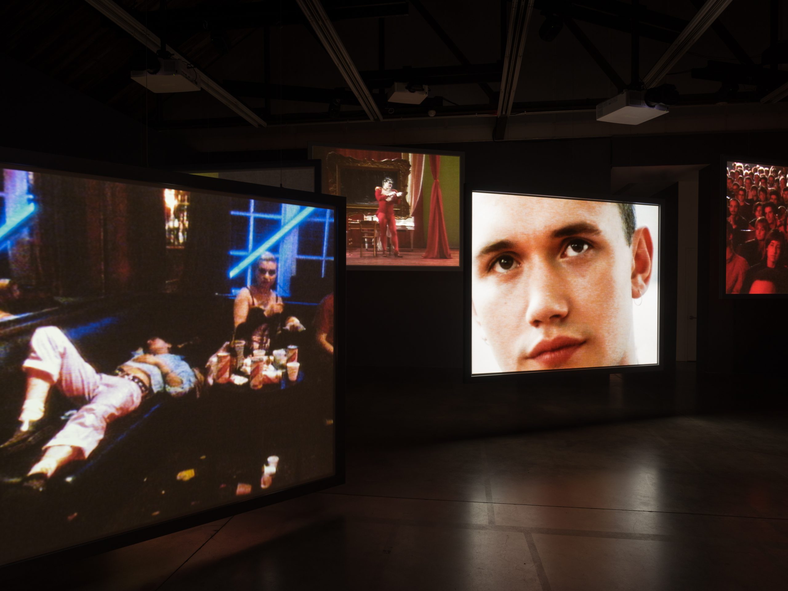 Many screens showing different videos simultaneously in a dark gallery