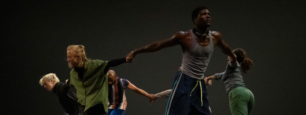 Multiple people dance on stage in the dark