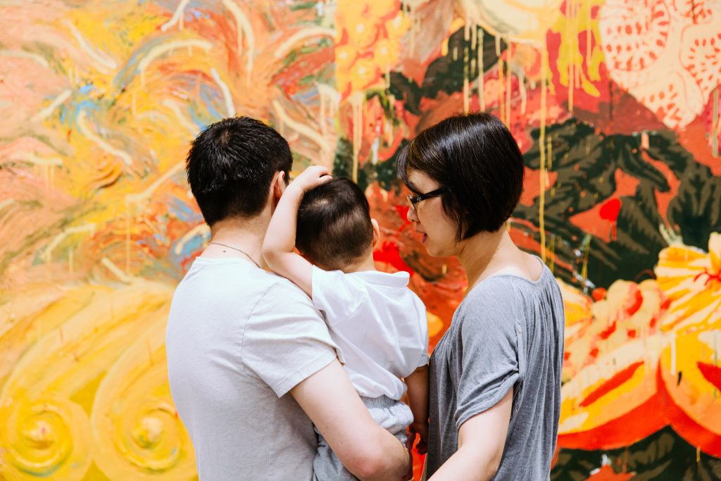 A family of three looks at a painting