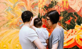 A family of three looks at a painting