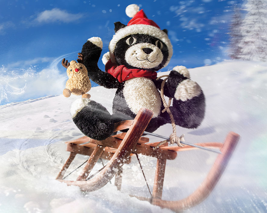 A christmas-themed stuffed cat rides a sled in the snow