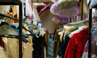 A narrow storage room filled with colorful, elaborate costumes